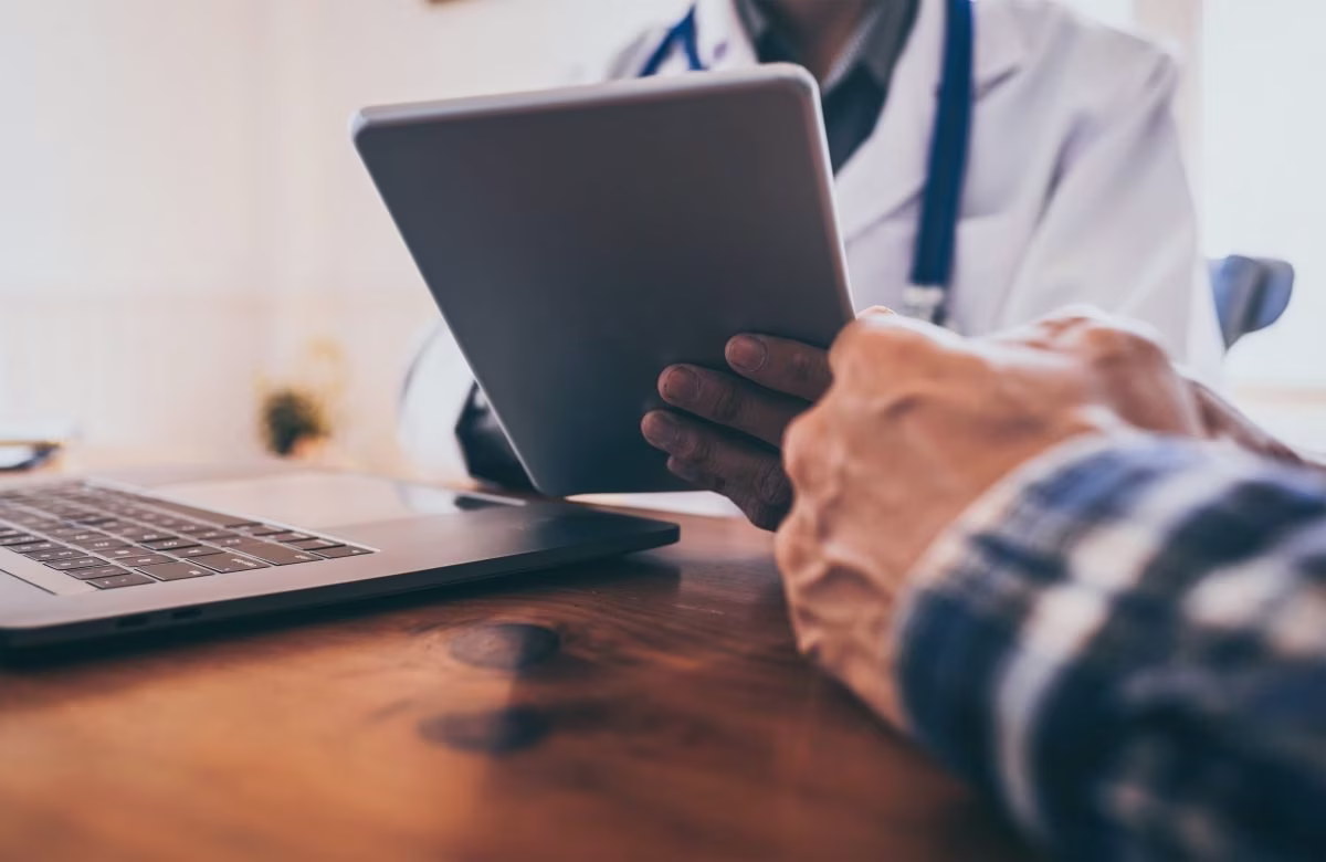 Health care provider looking at their tablet and talking to a client