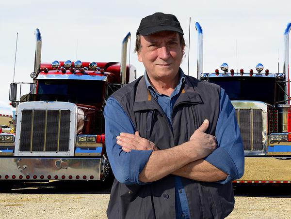 Commercial truck driver standing in front of his semi trucks