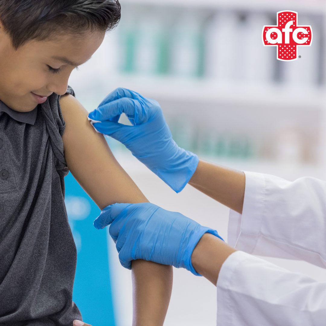 Physician wiping the arm of boy for vaccine