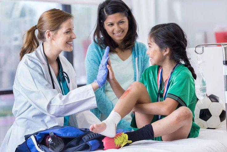 Physician high-fiving a girl soccer player after exam