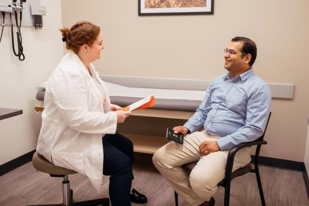 AFC physician going over immigration physical paperwork with male patient