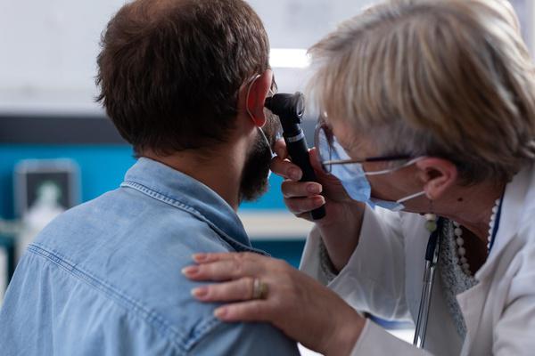 Provider examining a patient's ear with an otoscope