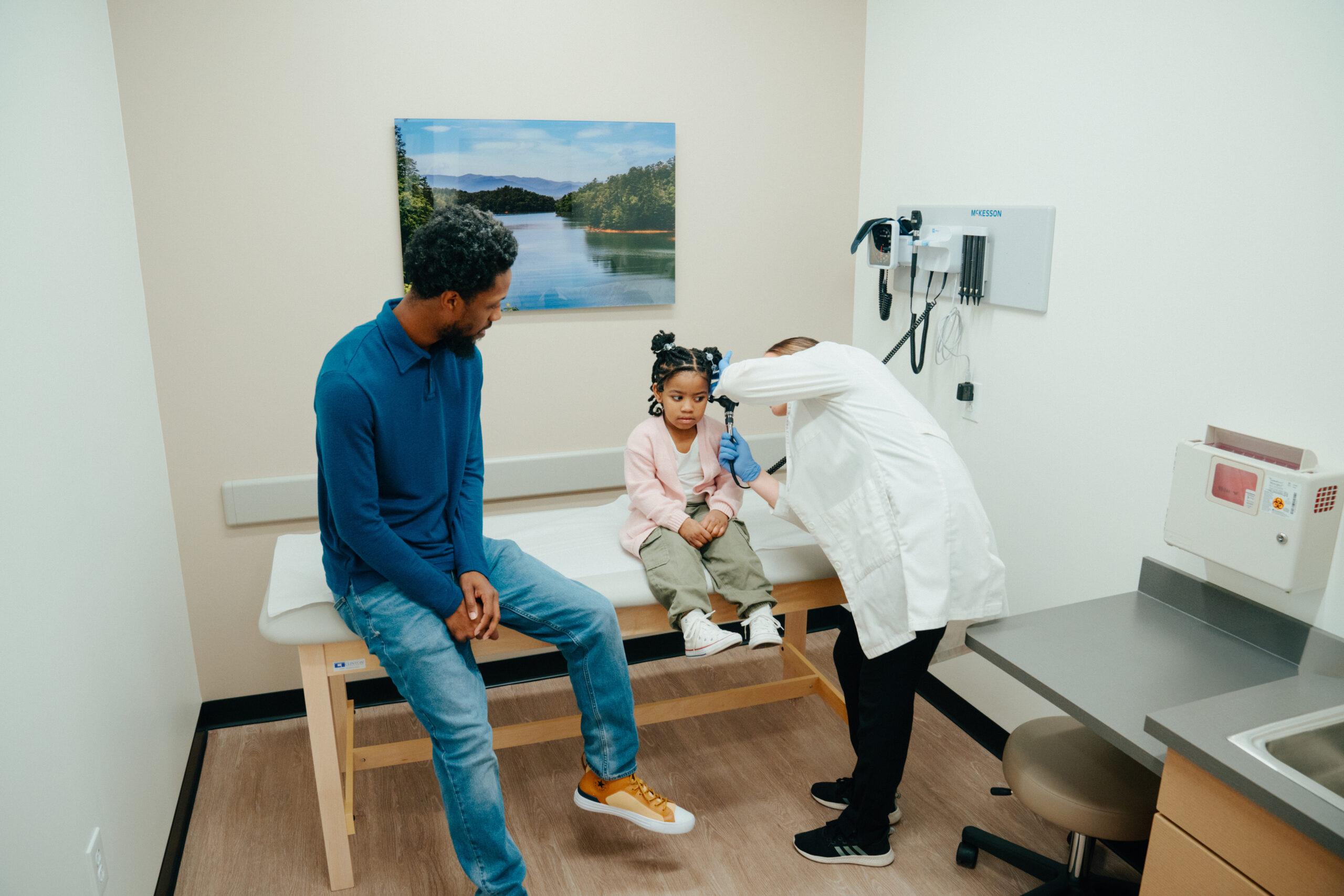 child receiving an ear exam at an urgent care.