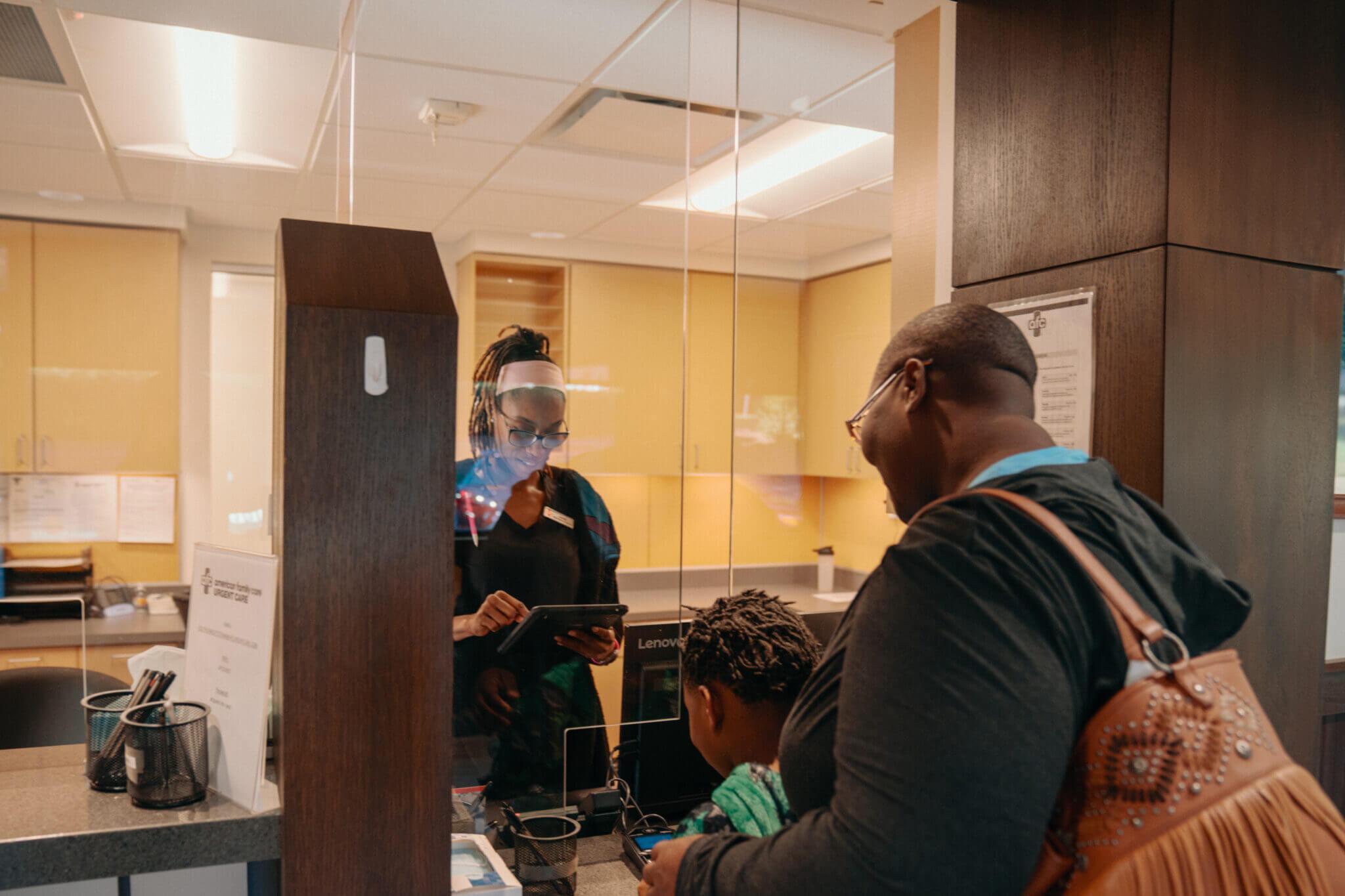 Mother and child being checked in at urgent care front desk