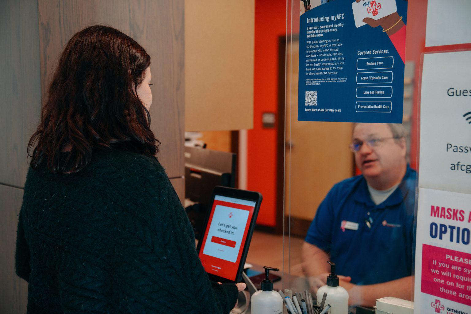 An AFC employee checking in a patient at the front desk