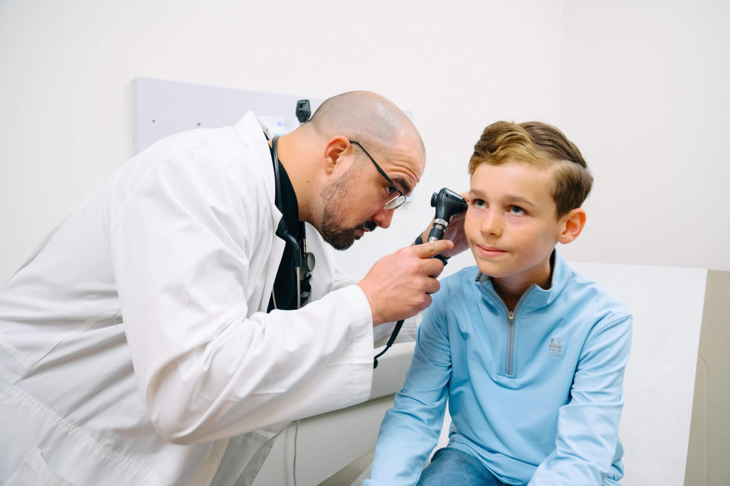 A young boy gets his ears checked by a healthcare provider.