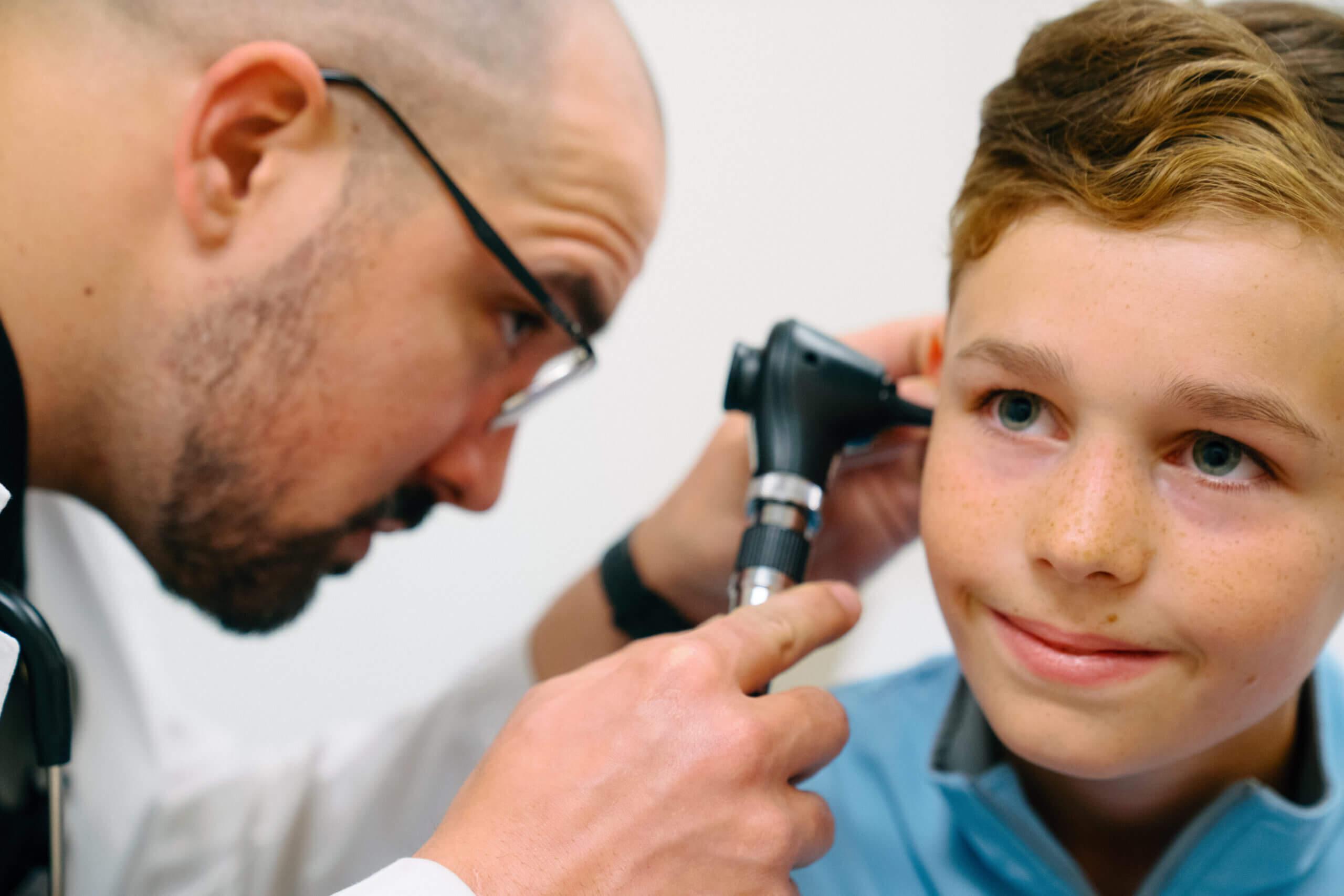 A young boy has his ears checked by a healthcare provider. 
