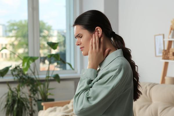 Woman holding her ear in discomfort at home