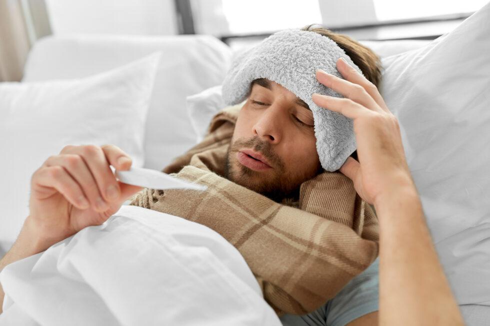 Man sick with the flu looking to see if he has a fever.