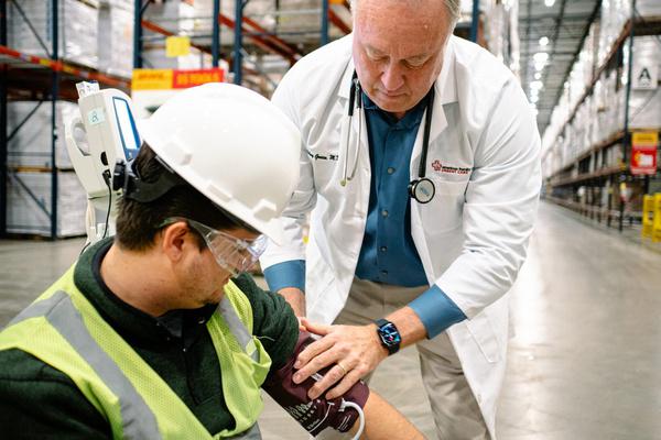 AFC provider checking a warehouse worker's blood pressure on site