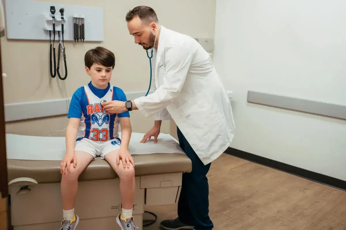 Doctor using a stethoscope during a child&rsquo;s sports or school physical