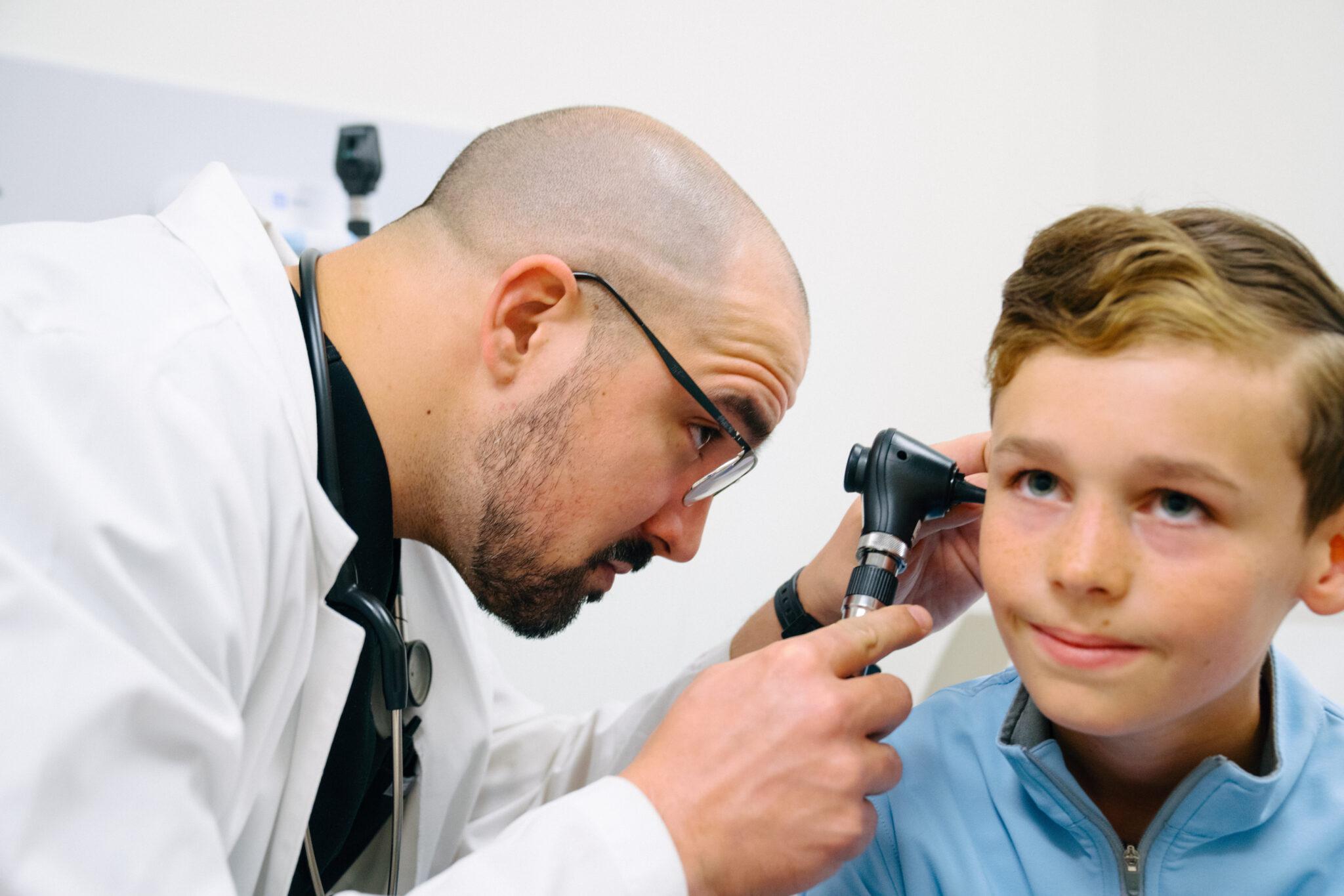 Smiling pediatric patient receiving a wellness exam from an AFC healthcare provider inside a modern urgent care clinic.