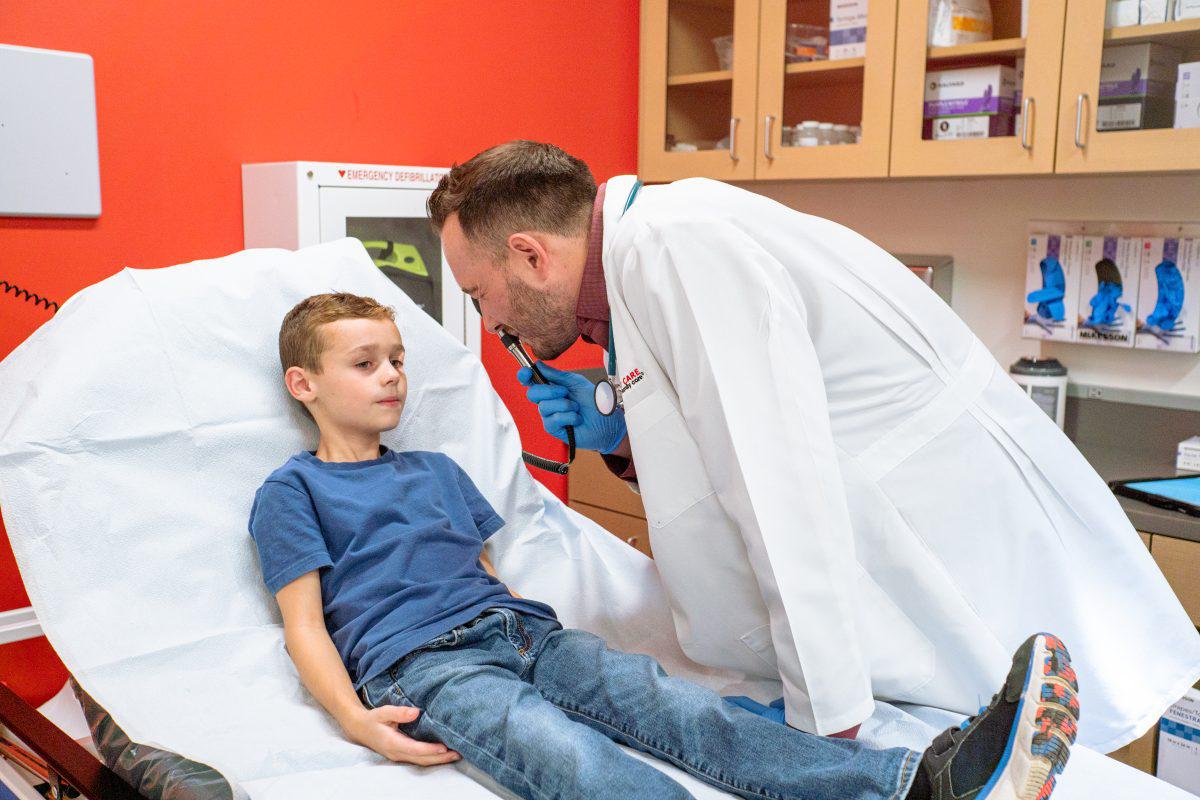 AFC provider shining light into young boy's eye, checking for Pink Eye
