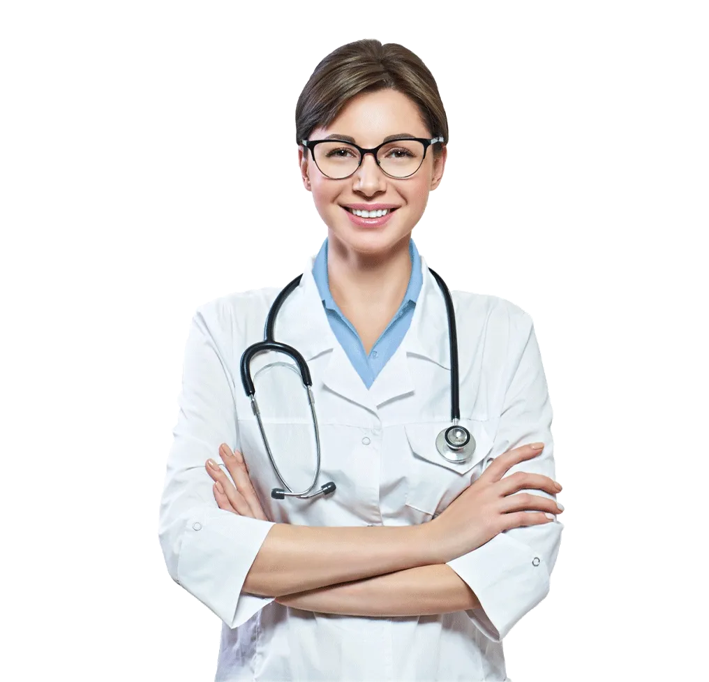 A smiling individual wearing glasses and a white doctor's coat with a stethoscope around their neck, standing with their arms crossed in the bustling hallway of a medical center.