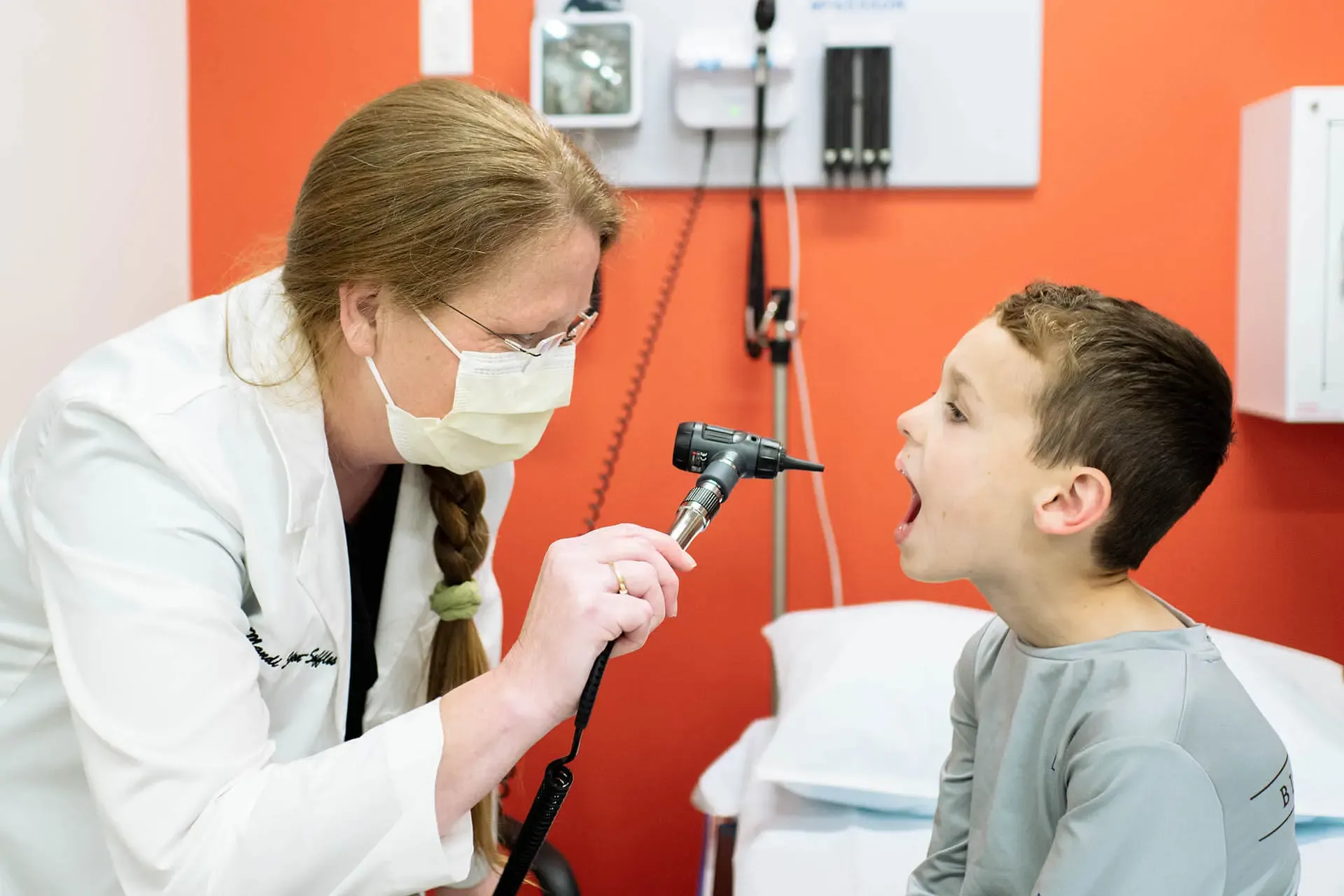 Physician checking inside a boy's mouth with a light