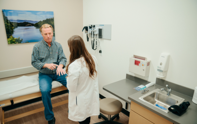 Doctor in a clinic examining a rash on a patient's forearm