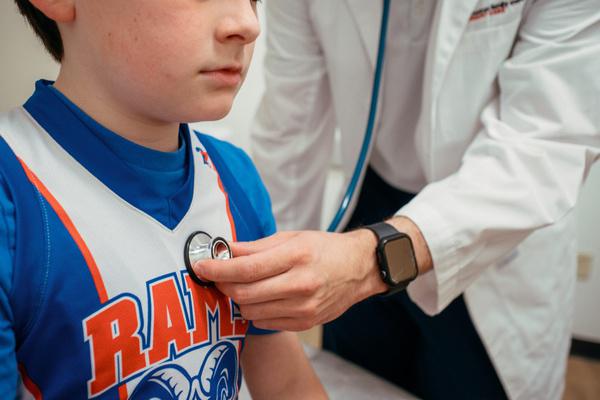 Provider listening to a young athlete's heart during a sports physical