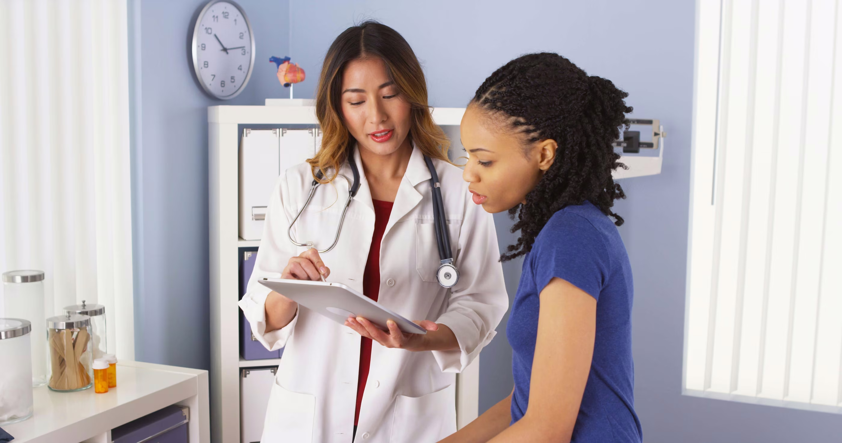 African American patient explaining issues to Asian doctor using
tablet