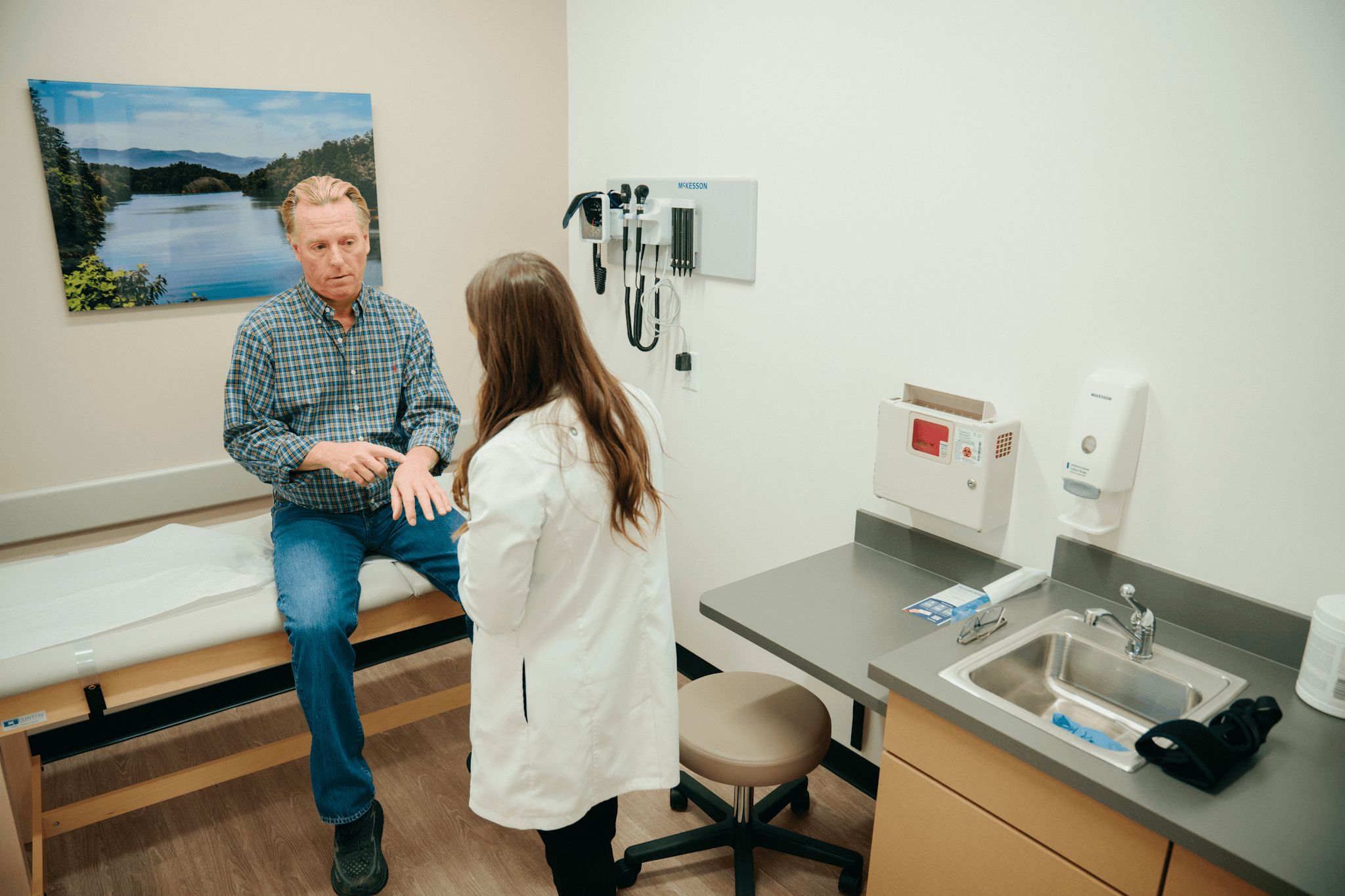 Doctor in a clinic examining a rash on a patient&rsquo;s forearm
