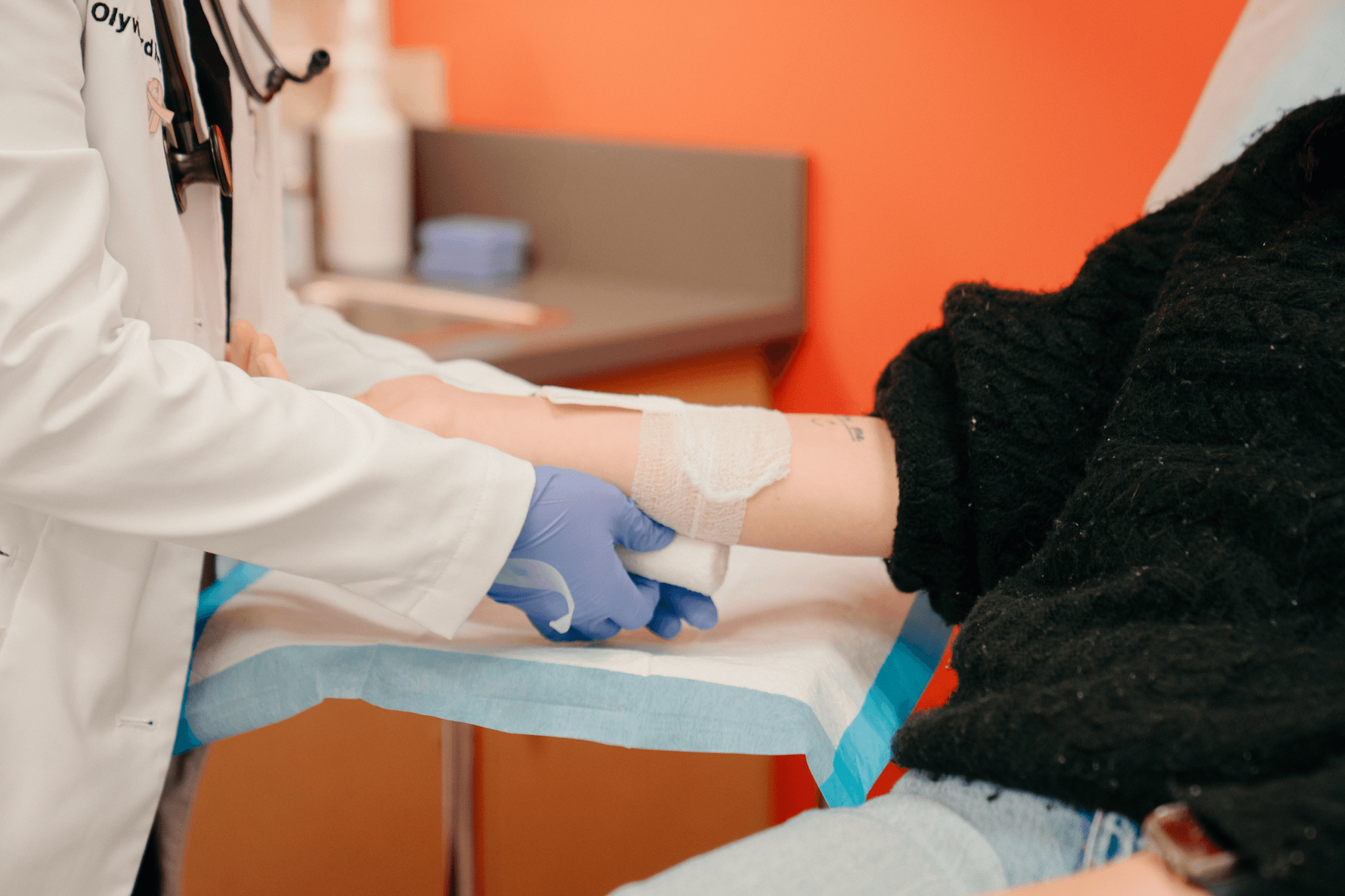 Doctor applying a bandage to a patient&rsquo;s injured forearm in a clinical setting