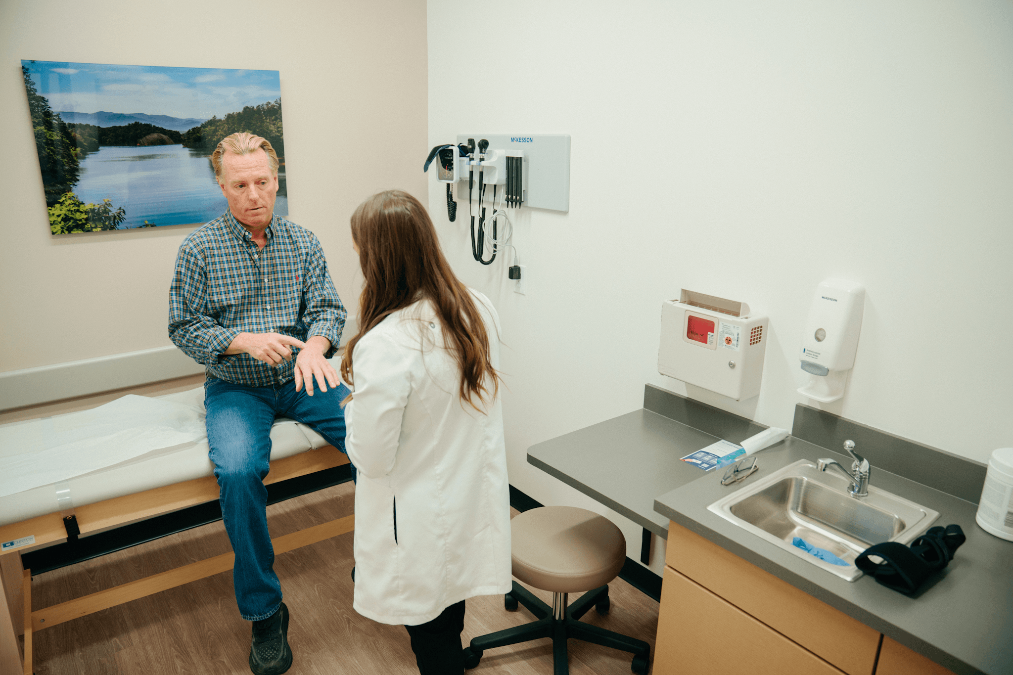 Doctor in a clinic examining a rash on a patient&rsquo;s forearm