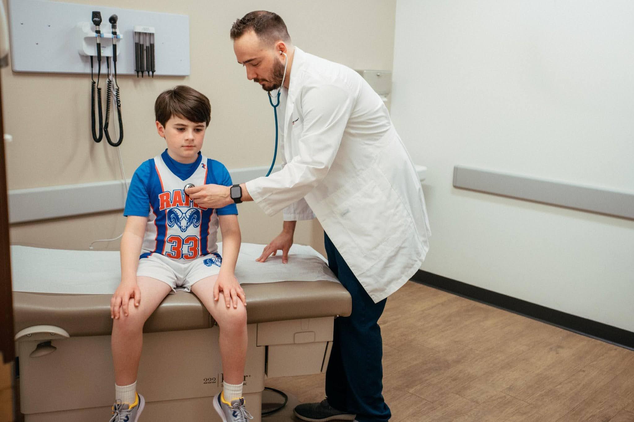 Doctor using a stethoscope during a child’s sports or school physical