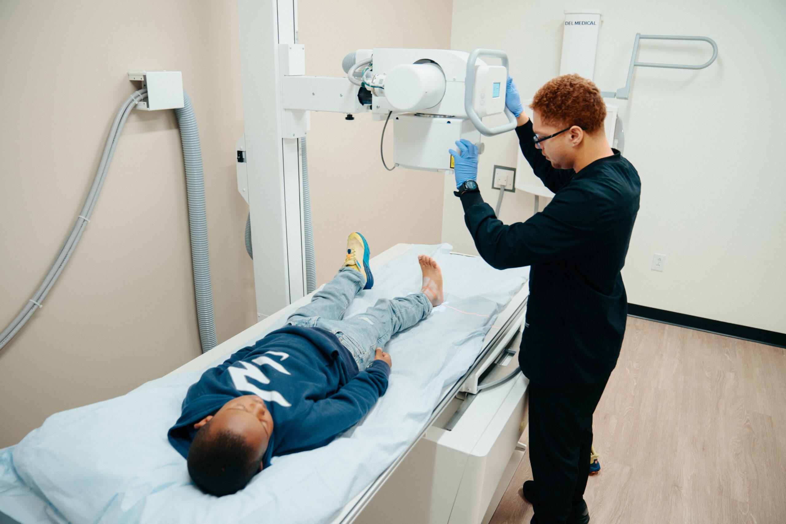 Young boy lying on an examination table while a physician performs an X-ray procedure.